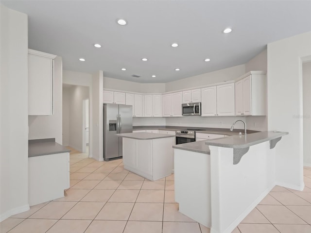 kitchen featuring white cabinetry, light tile patterned floors, kitchen peninsula, a kitchen island, and stainless steel appliances