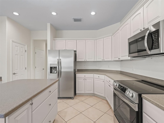 kitchen with stainless steel appliances, white cabinets, and light tile patterned flooring