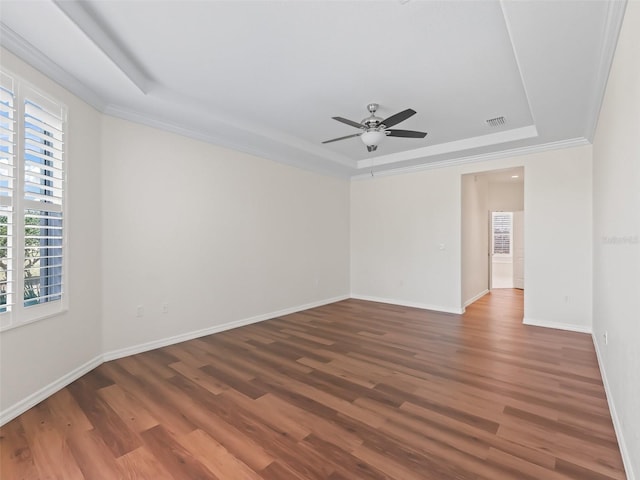 unfurnished room with dark hardwood / wood-style flooring, a tray ceiling, crown molding, and ceiling fan