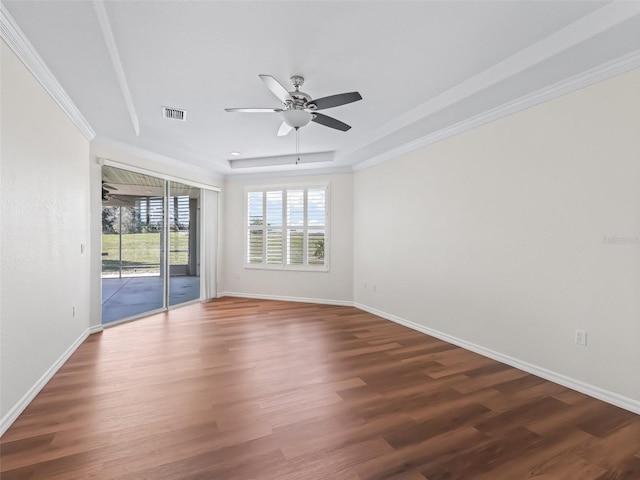 unfurnished room with dark hardwood / wood-style flooring, a tray ceiling, crown molding, and ceiling fan