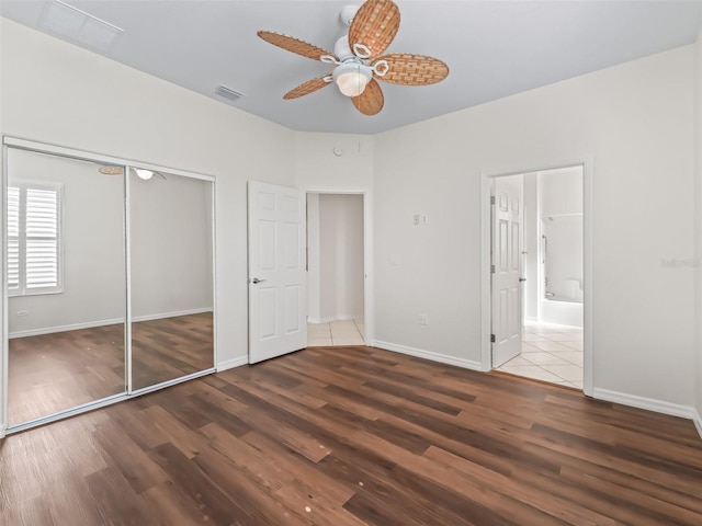 unfurnished bedroom with wood-type flooring, connected bathroom, ceiling fan, and a closet