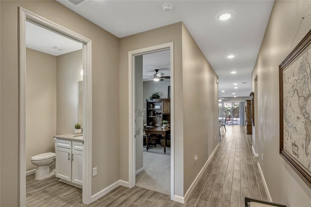 corridor with baseboards, wood finish floors, and recessed lighting