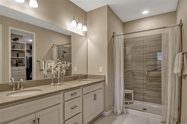 full bath featuring double vanity, marble finish floor, a shower stall, and a sink