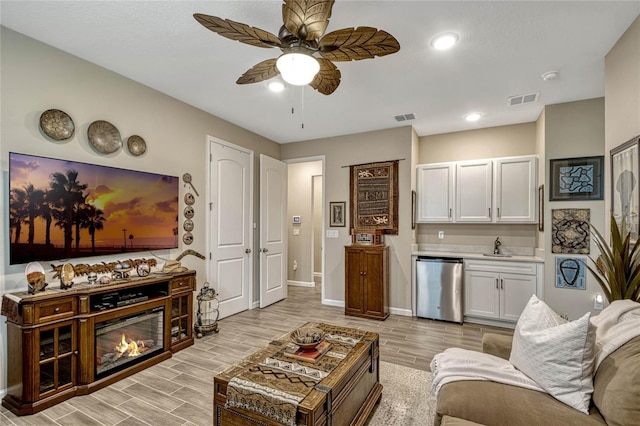 living room with baseboards, visible vents, a ceiling fan, wood tiled floor, and indoor wet bar