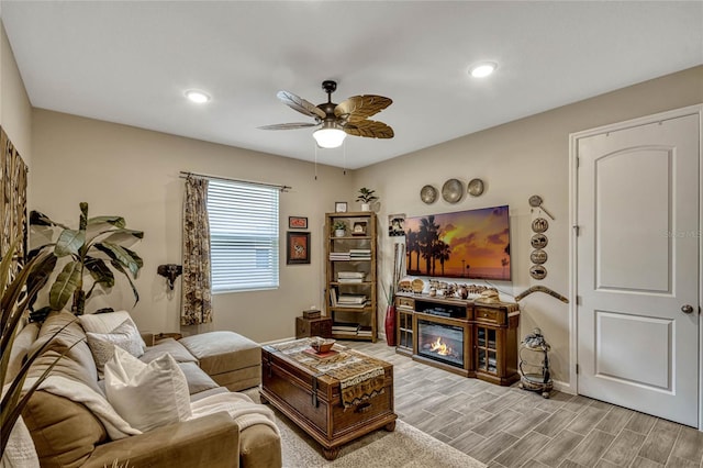 living room with a glass covered fireplace, ceiling fan, recessed lighting, and wood tiled floor