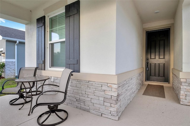 view of exterior entry featuring covered porch and stucco siding