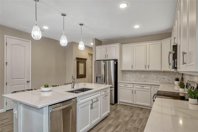 kitchen featuring a center island with sink, appliances with stainless steel finishes, white cabinets, and a sink