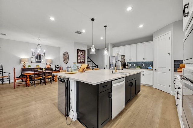 kitchen with wine cooler, sink, a center island with sink, pendant lighting, and white cabinets