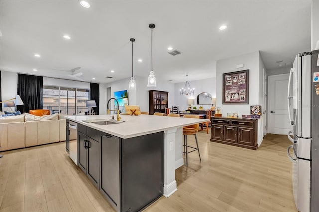 kitchen with sink, dark brown cabinets, a kitchen breakfast bar, an island with sink, and stainless steel appliances