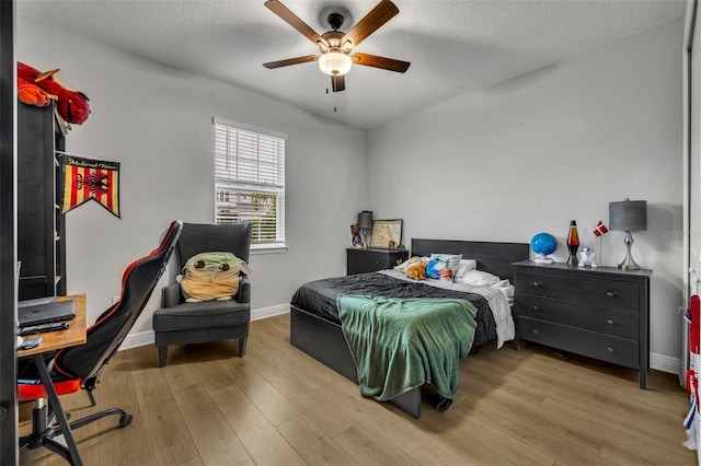 bedroom with ceiling fan, light hardwood / wood-style flooring, and a textured ceiling