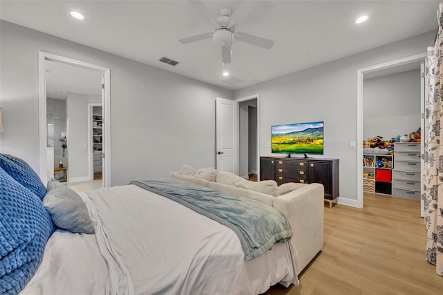 bedroom with a walk in closet, light hardwood / wood-style floors, a closet, and ceiling fan