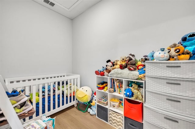 bedroom with hardwood / wood-style flooring and a nursery area