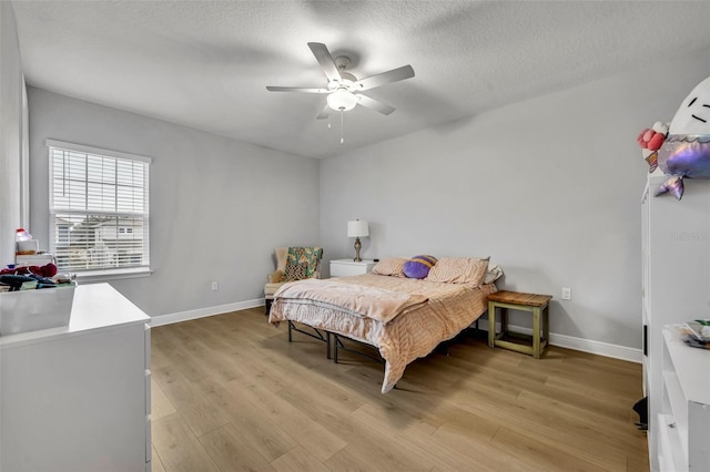 bedroom with a textured ceiling, ceiling fan, and light hardwood / wood-style floors