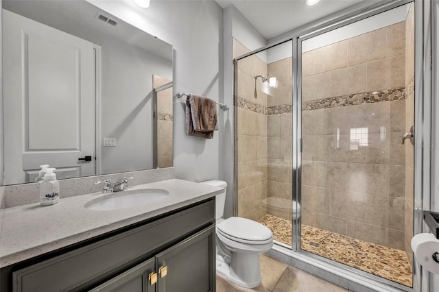 bathroom featuring tile patterned floors, toilet, a shower with shower door, and vanity