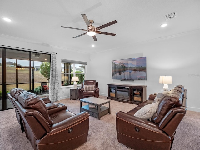 living room with light carpet, a fireplace, ornamental molding, and ceiling fan