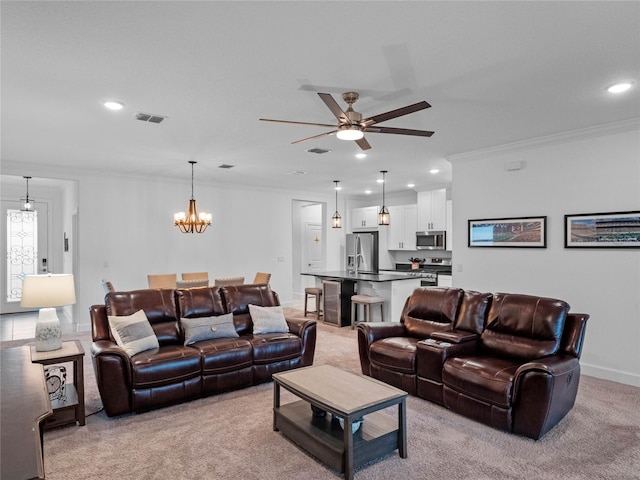 living room with crown molding, ceiling fan with notable chandelier, and light carpet