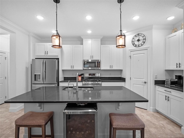 kitchen with appliances with stainless steel finishes, a kitchen island with sink, pendant lighting, and white cabinets