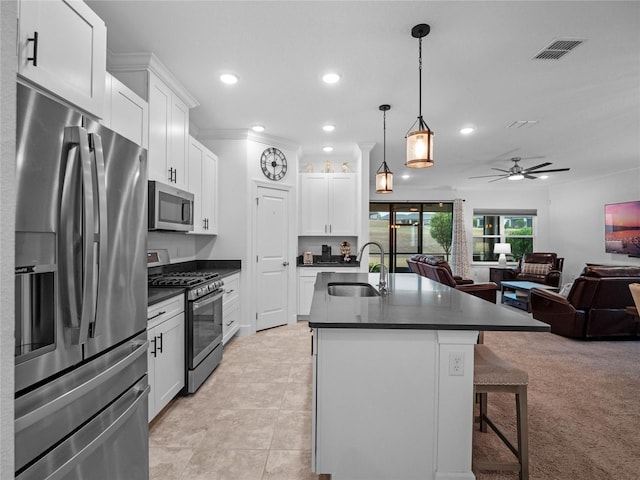 kitchen featuring white cabinetry, stainless steel appliances, sink, and hanging light fixtures