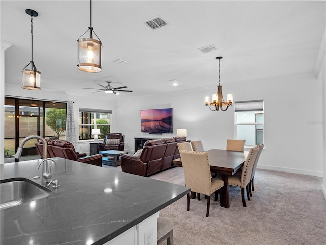 dining space featuring light carpet, sink, ceiling fan with notable chandelier, and crown molding