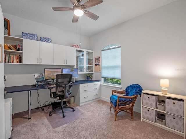 office with built in desk, light carpet, and ceiling fan