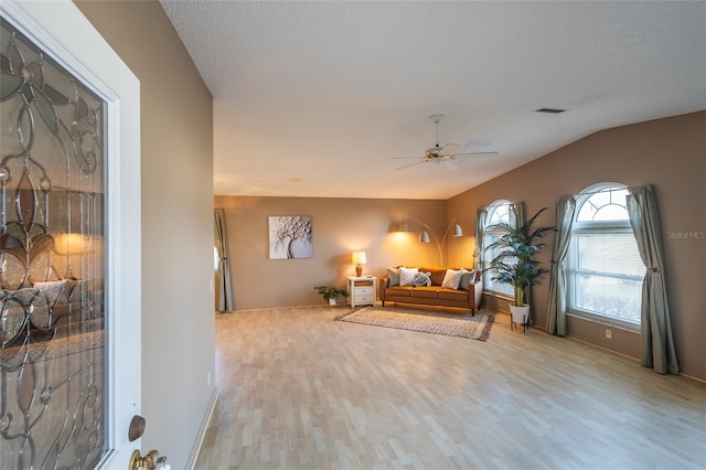 bedroom featuring lofted ceiling, ceiling fan, light hardwood / wood-style floors, and a textured ceiling