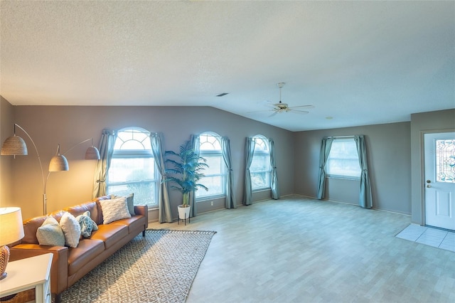 living room featuring lofted ceiling, ceiling fan, a textured ceiling, and light wood-type flooring