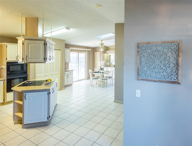 kitchen featuring ceiling fan, light tile patterned floors, a textured ceiling, and black appliances