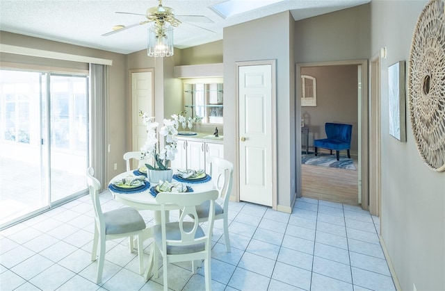 tiled dining space with a textured ceiling and ceiling fan