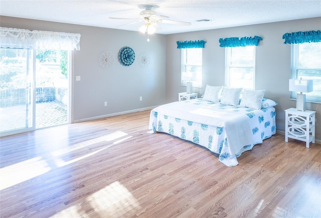 bedroom featuring access to exterior, light hardwood / wood-style floors, and multiple windows