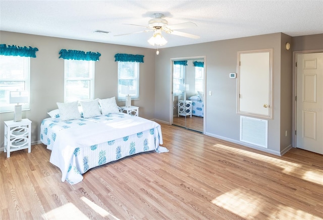 bedroom with ceiling fan, light hardwood / wood-style flooring, and a textured ceiling