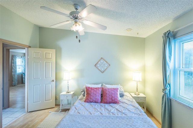 bedroom featuring ceiling fan, a textured ceiling, and light hardwood / wood-style flooring