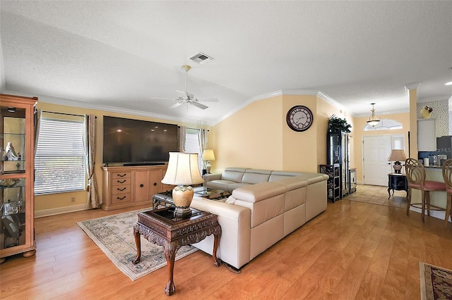 living room with lofted ceiling, crown molding, light hardwood / wood-style flooring, and a textured ceiling