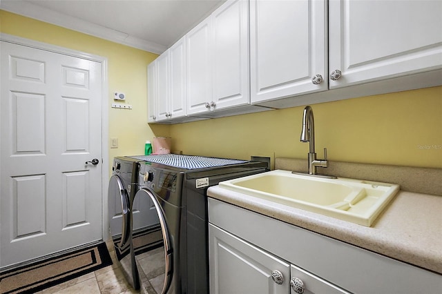 laundry area featuring light tile patterned flooring, sink, crown molding, cabinets, and washing machine and dryer