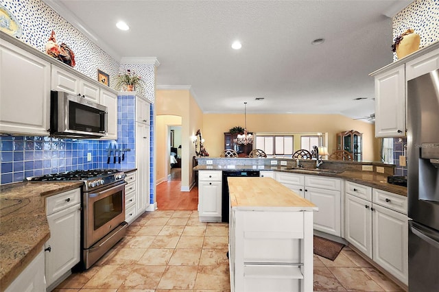 kitchen featuring wood counters, appliances with stainless steel finishes, kitchen peninsula, and white cabinets