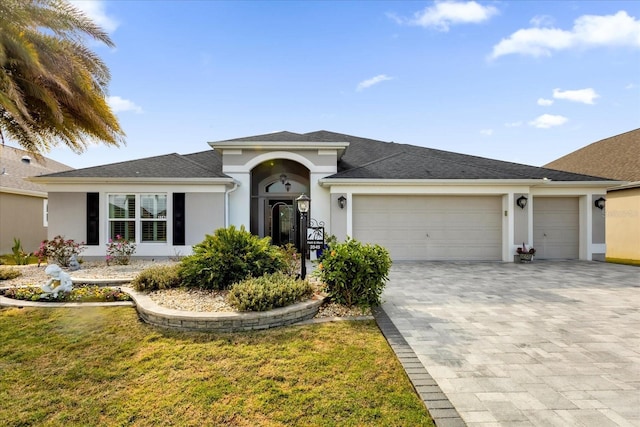 single story home with a garage, decorative driveway, a front yard, and stucco siding