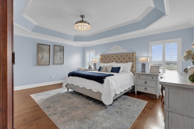 bedroom featuring dark wood-style floors, a tray ceiling, and multiple windows