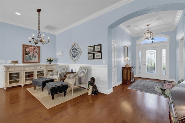 foyer featuring crown molding, dark wood-type flooring, and a chandelier