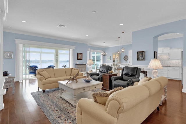 living room featuring crown molding, dark hardwood / wood-style floors, and a notable chandelier