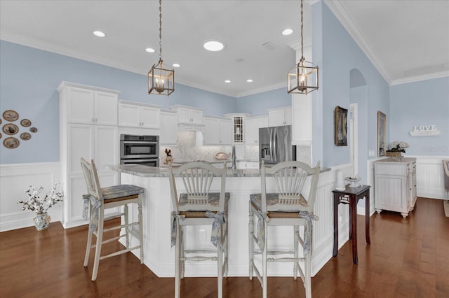 kitchen with light stone countertops, appliances with stainless steel finishes, ornamental molding, and pendant lighting