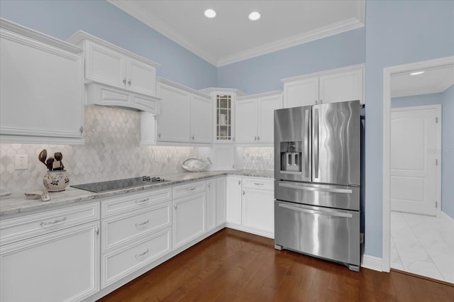 kitchen featuring white cabinetry, backsplash, stainless steel fridge, light stone countertops, and black electric cooktop