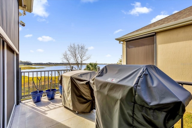 view of patio with a balcony, a water view, and a grill