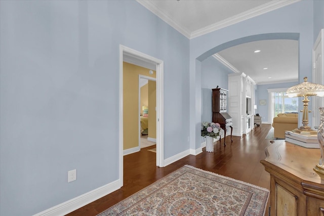 corridor featuring arched walkways, ornamental molding, dark wood finished floors, and baseboards