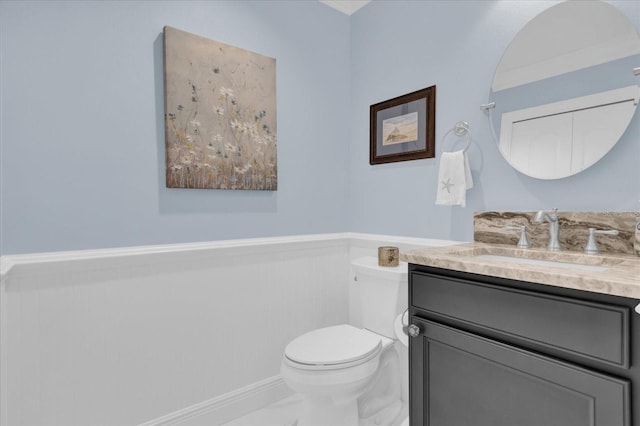 bathroom with a wainscoted wall, marble finish floor, toilet, and vanity