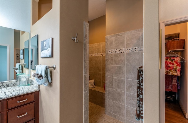 bathroom featuring hardwood / wood-style flooring, tiled shower, and vanity