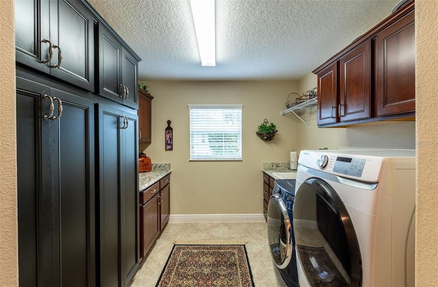 laundry room featuring cabinets, washing machine and clothes dryer, and a textured ceiling