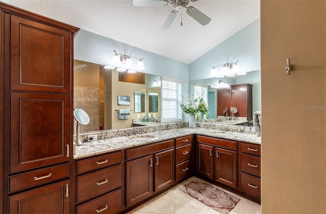 bathroom with lofted ceiling, tile patterned flooring, vanity, ceiling fan, and walk in shower