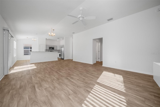 unfurnished living room featuring lofted ceiling, ceiling fan with notable chandelier, and light hardwood / wood-style floors