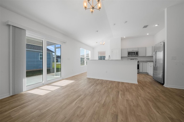 unfurnished living room featuring lofted ceiling, a notable chandelier, sink, and light wood-type flooring