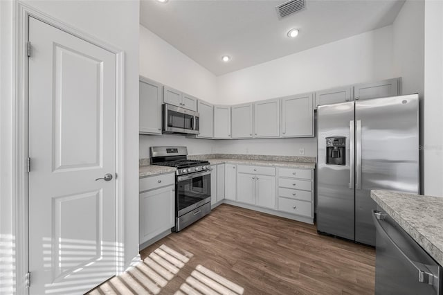 kitchen with gray cabinetry, light wood-type flooring, and appliances with stainless steel finishes