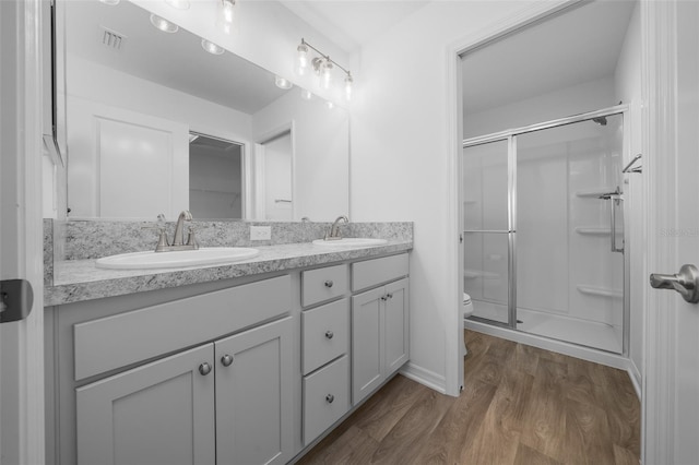 bathroom with an enclosed shower, vanity, hardwood / wood-style flooring, and toilet